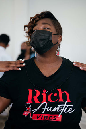 Black woman wearing black face mask and black t-shirt that says "Rich Auntie Vibes"
